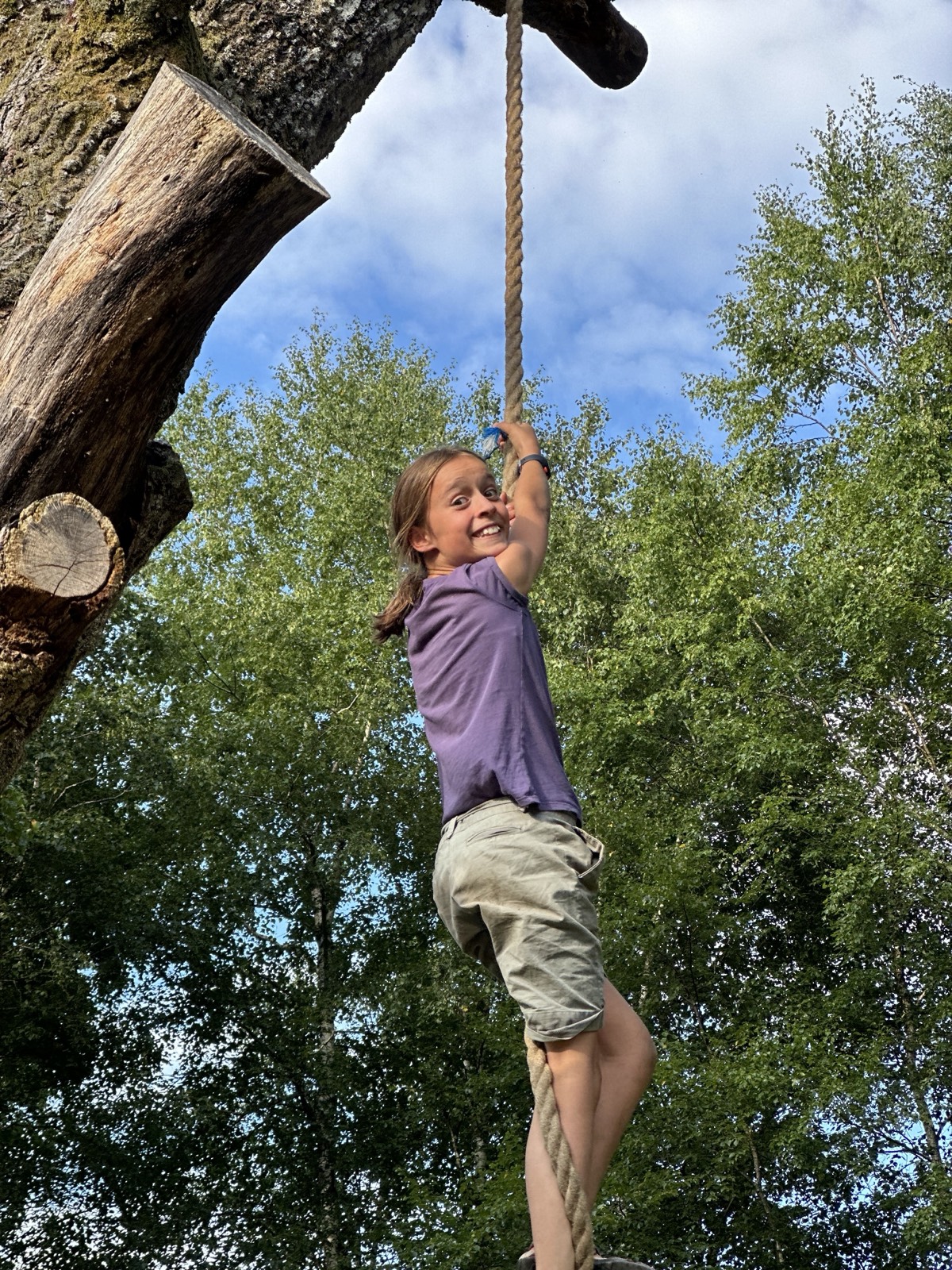 Femme suspendue à une corde tendue entre deux troncs, en forêt