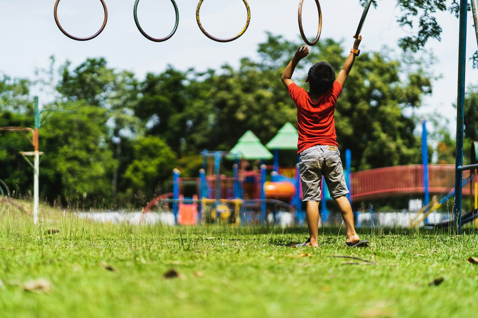 Enfant s'élançant vers des anneaux de suspension en extérieur